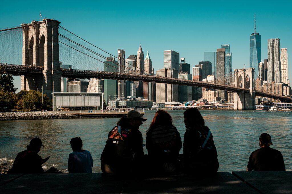 People admiring the Brooklyn Bridge and the Manhattan skyline from Brooklyn New York