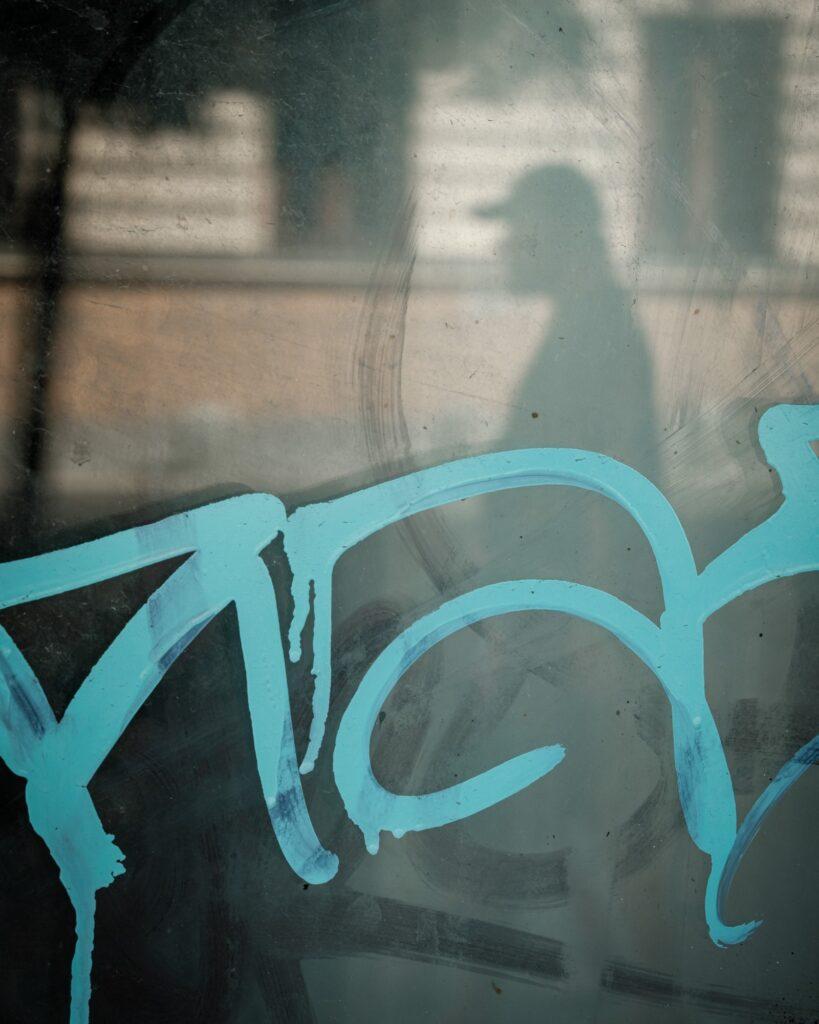 A man's reflection in a graffitti painted window in Bucharest Romania