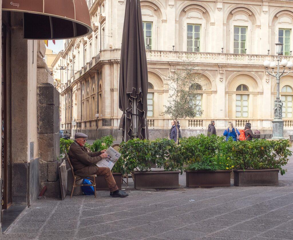 Old man reading a newspaper outside a cafe in Catania Sicily