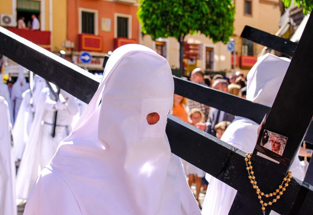 White nazareno with cross during the Semana Santa procession in Seville Spain