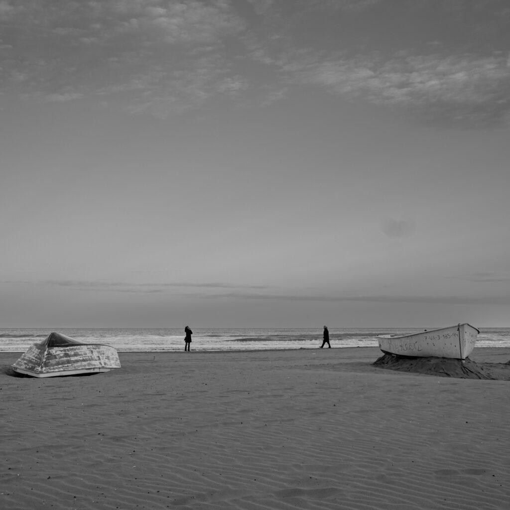 Minimalist beach scene in Valencia Spain with people walking near the sea